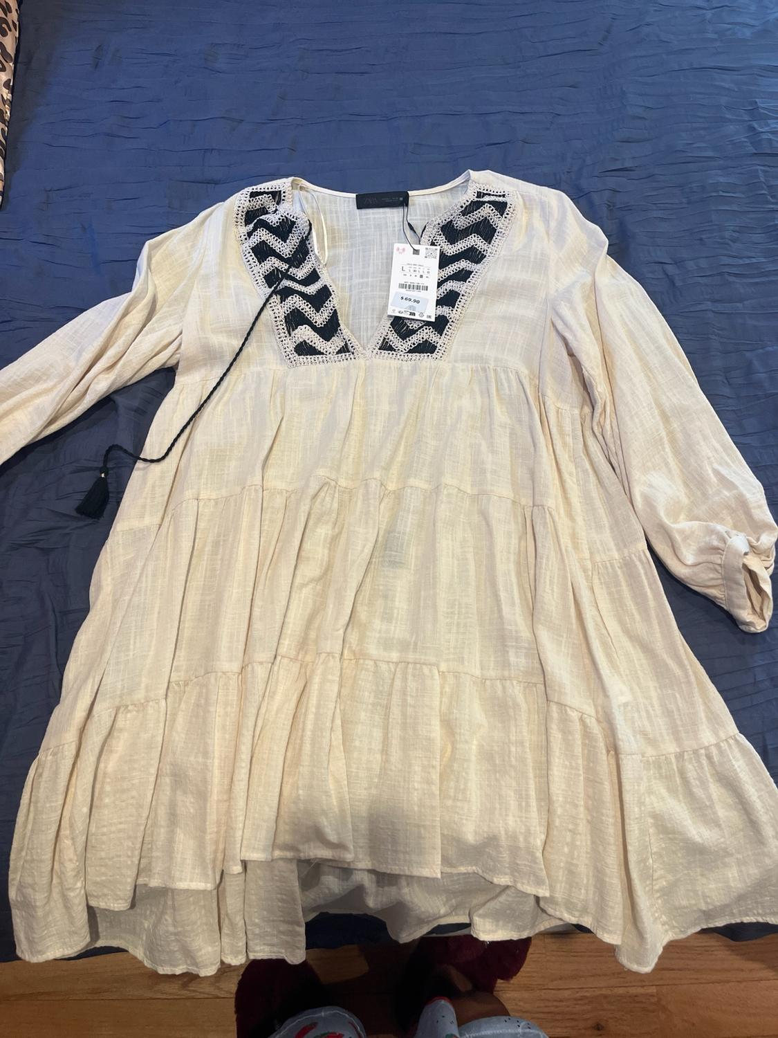 Beige long-sleeved frill dress with V-neck and black geometric pattern, on blue fabric. Label reads: ZARA L $69.90.