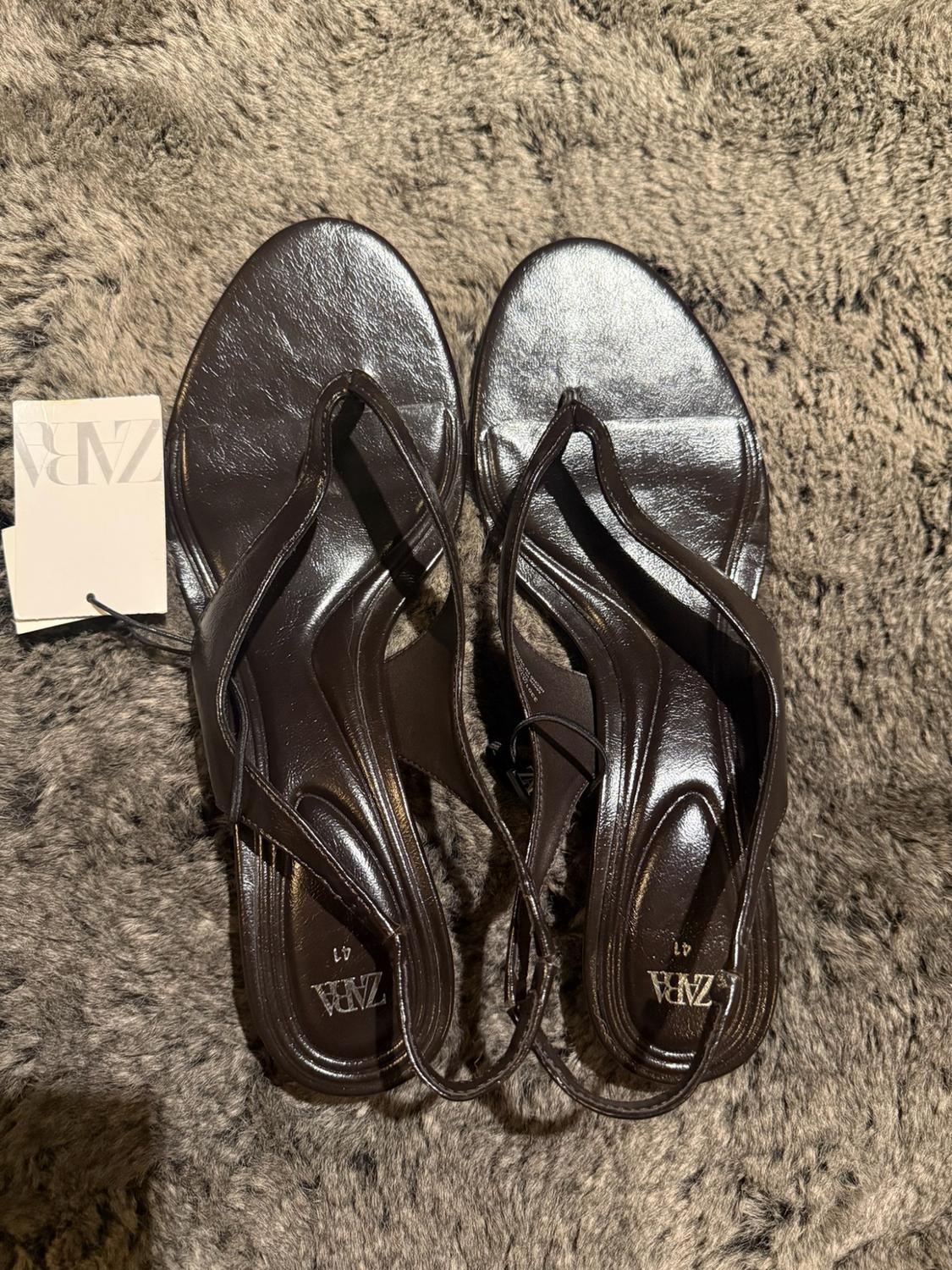 Dark brown strappy sandals on a furry surface. They have a label with the text ZARA. The insoles read ZARA and 41.