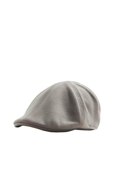 Grey flat cap on a white background, showing detailed stitching and soft texture.