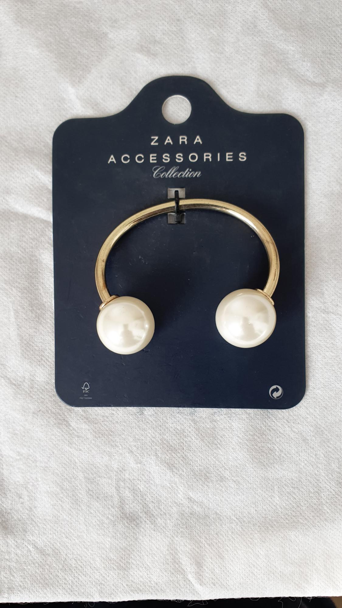 Gold pendant with white pearls on a black card with the text "ZARA ACCESSORIES Collection", on a white background.