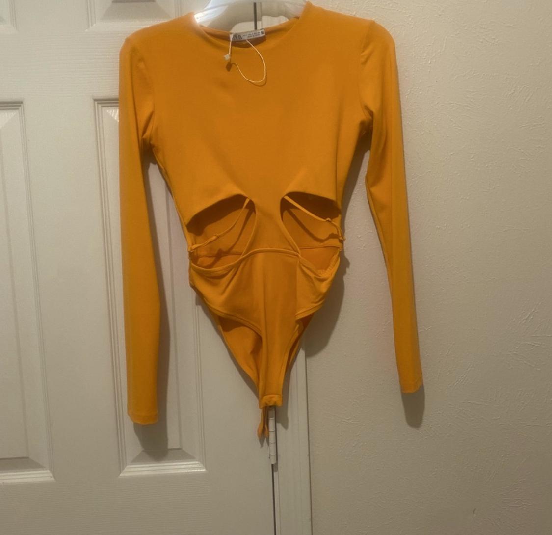Front view of yellow bodysuit with long sleeves and cut-outs on the torso.