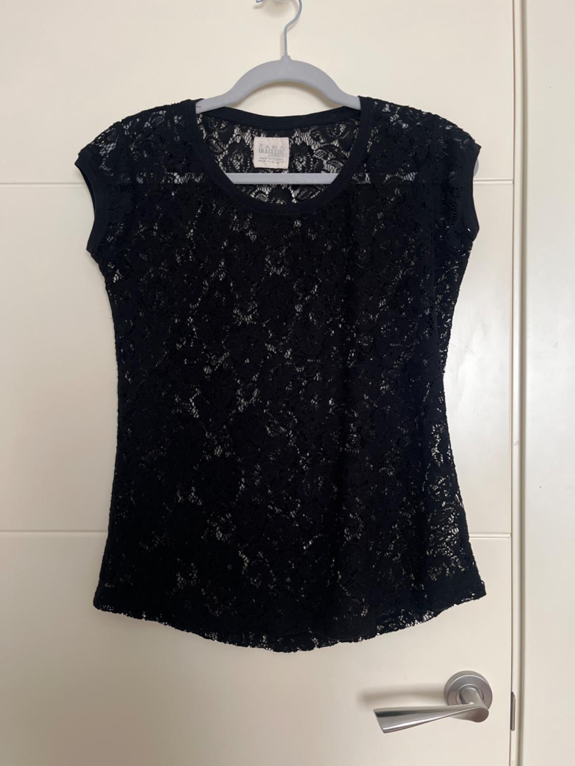 Front view of a black lace blouse with a round neck and short sleeves.