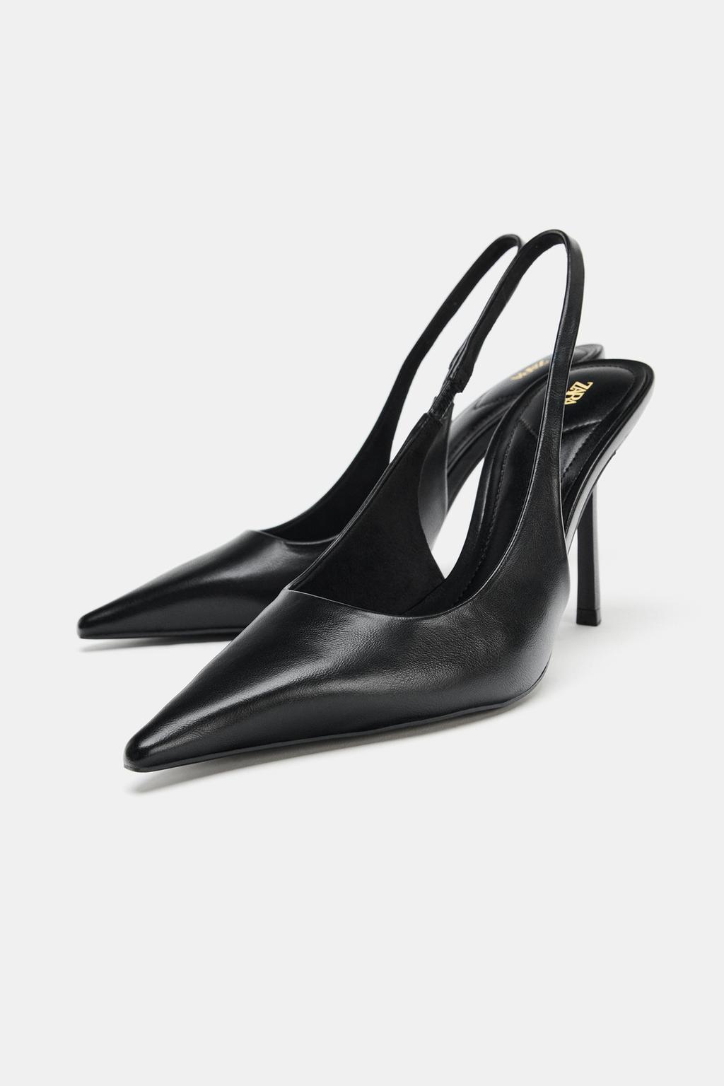 Black high heels with a pointed toe and open back. Gold logo detail on the insole.