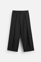 Wide fit pants. Front pleats at waist. Side pockets and back welt pockets. Front zip and hidden metal hook closure.