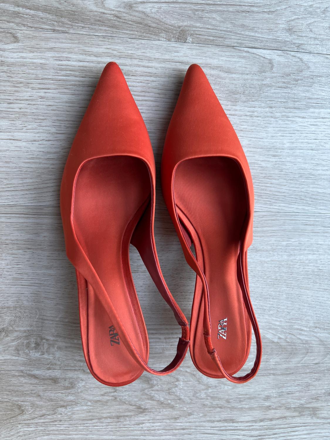 Orange slingback heels with a pointed toe on a wooden floor. Zara text on the insole.