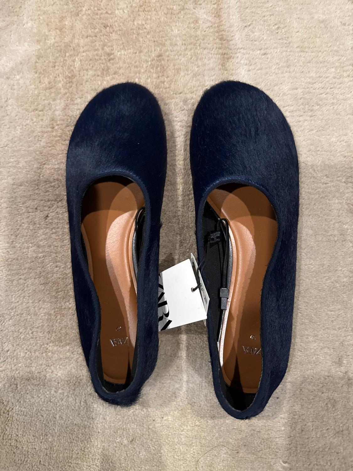 Navy blue textured faux fur flats on a beige rug. Top view. Visible text: ZARA.