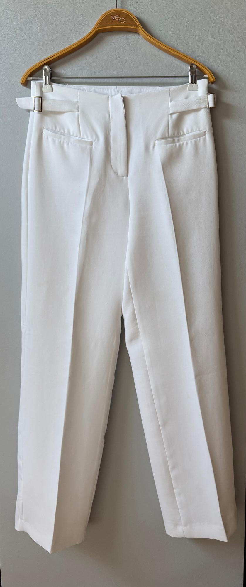 White trousers hanging on a wooden hanger with the "Yera" brand visible, light grey background.