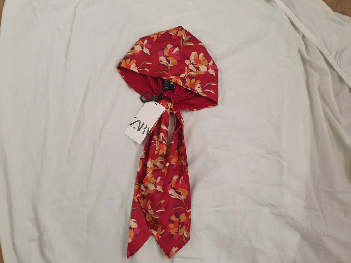 Red scarf with yellow and pink floral print on white fabric. Visible label with the text "ZARA".