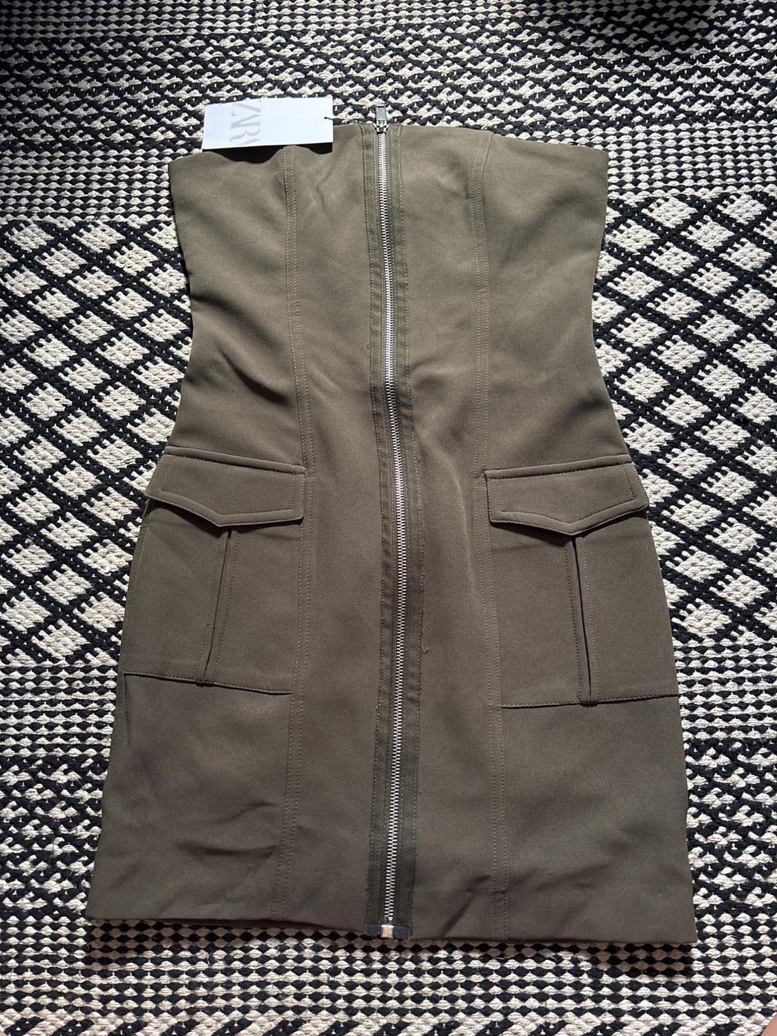 Front view of green dress with central zip and front pockets.
