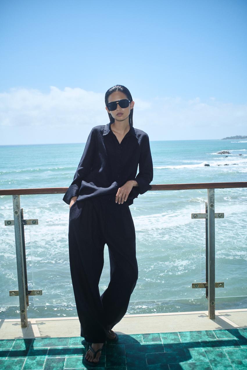 Black long-sleeved button-down collared shirt set with wide-leg black pants featuring side pockets and sunglasses.