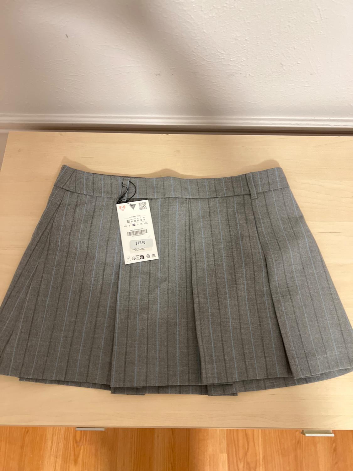 Grey skirt with vertical stripes on a light wooden table. Visible tag with price of $45.90. White wall background.