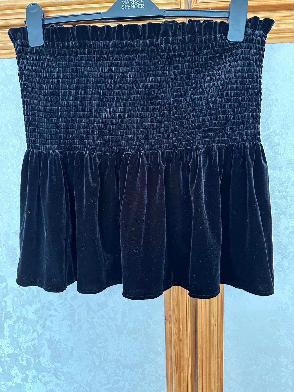 Front view of black skirt with gathers and ruffles at the waist and the hem.
