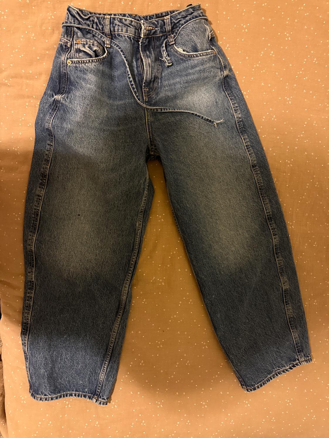 Blue, straight-cut jeans with an elasticated drawstring waist, on a brown surface with small white dots.