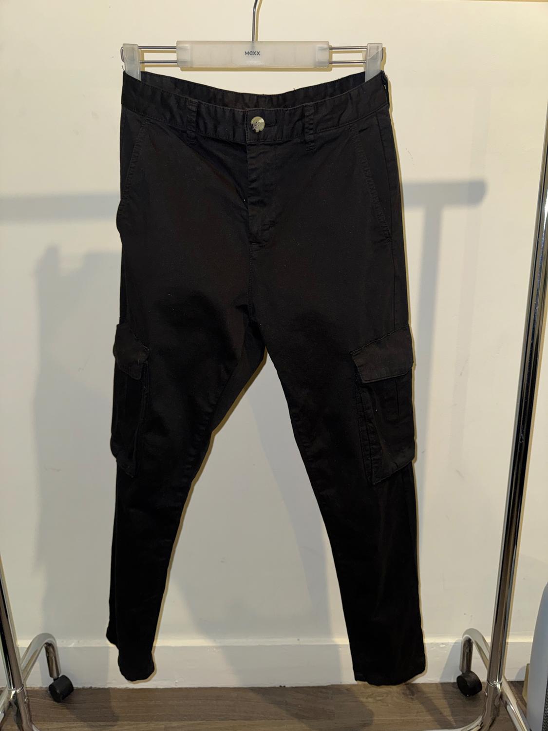 Black cargo trousers hanging on a hanger with a white background. The hanger has the brand "MEXX".