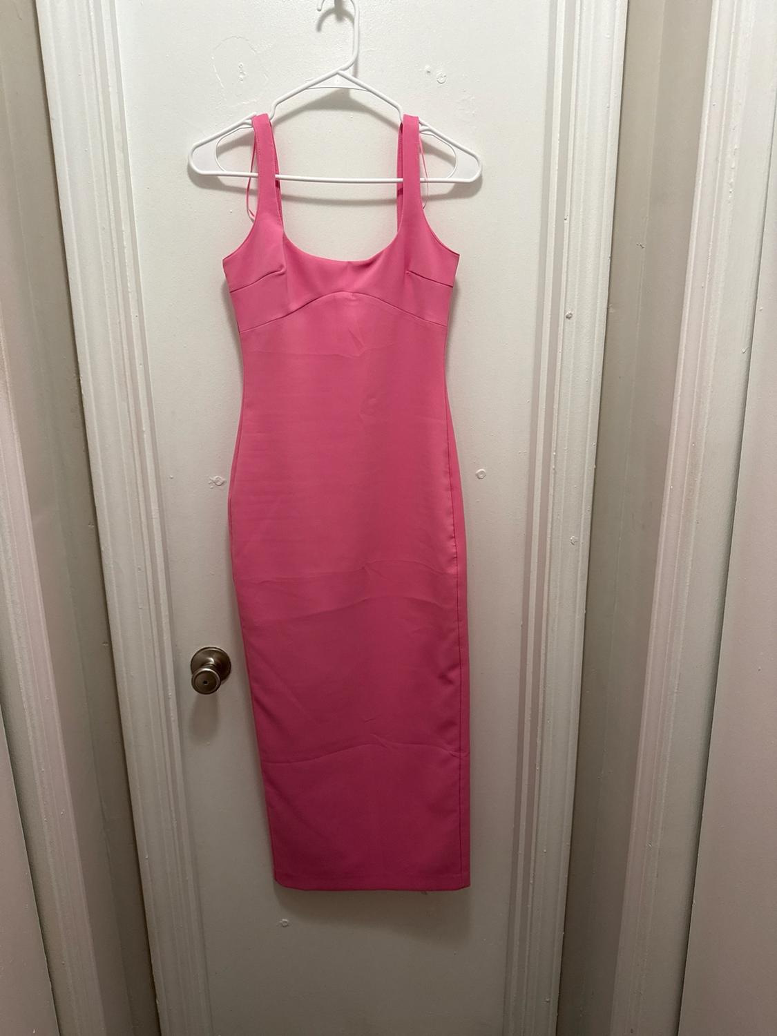 Pink camisole dress with seam detail, hanging on a hanger on a white interior door.
