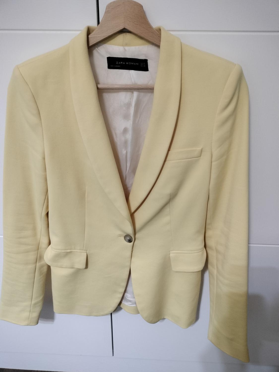 Front view of a yellow blazer with lapel, front button and flap pockets.