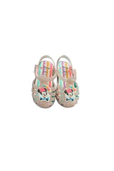 Transparent children's sandals featuring a Minnie Mouse design and a multicolored striped insole. Visible text: "Disney Minnie 23".