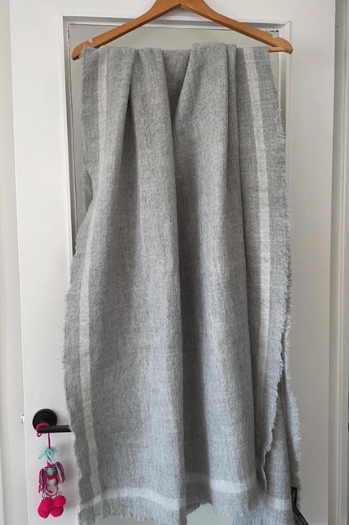 Front view of a grey scarf with light stripes hanging on a door.