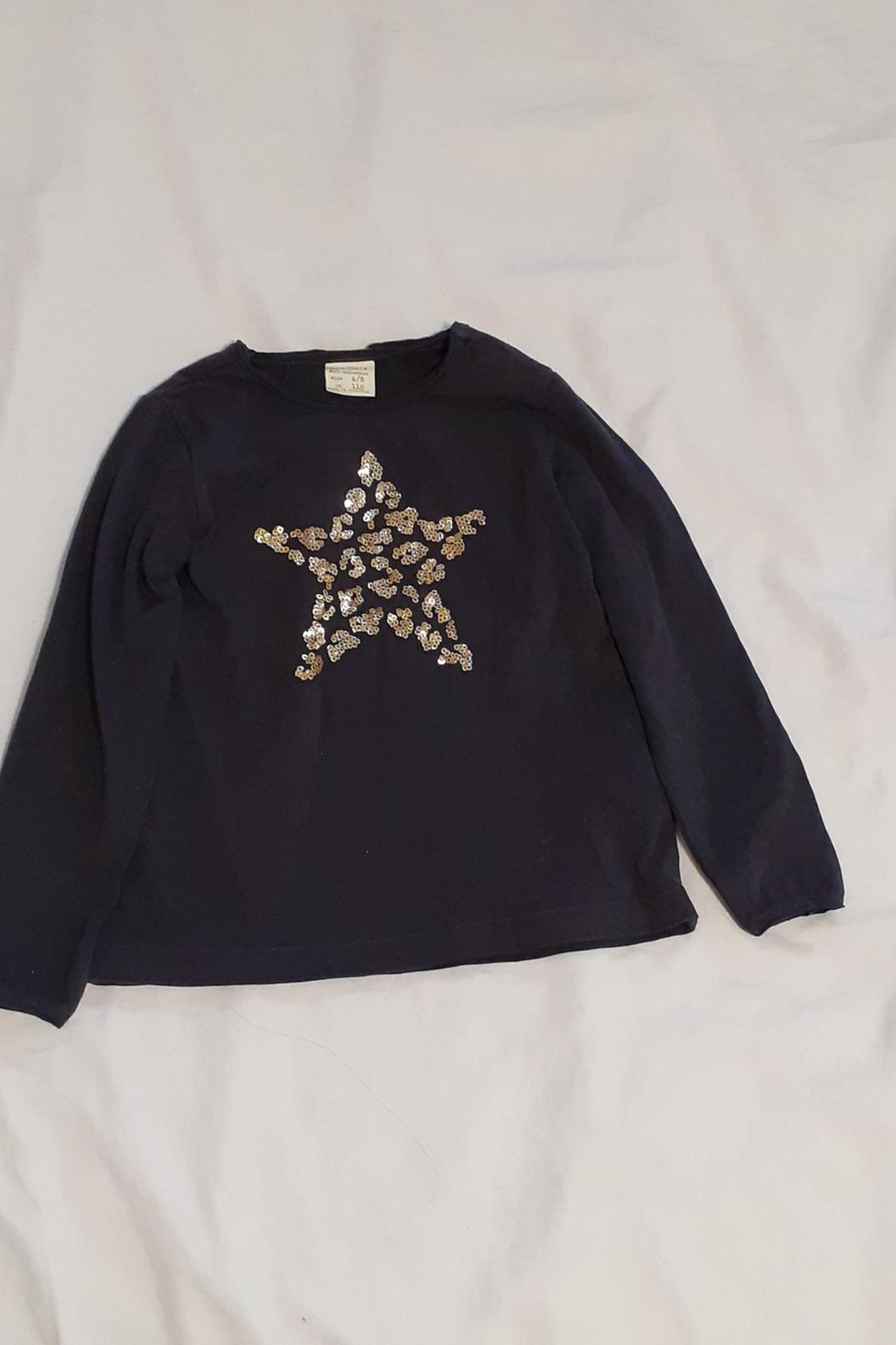 Front view of black jumper with gold sequin star on chest.