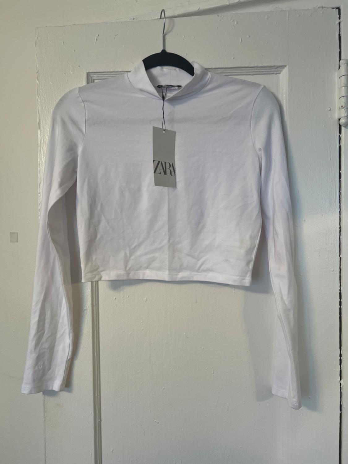 Front view of a white long-sleeved t-shirt with a hang tag.