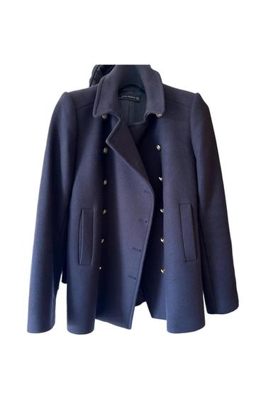 Navy blue coat with gold buttons and wide lapels. Visible inner label with text: "Zara Woman". White background.