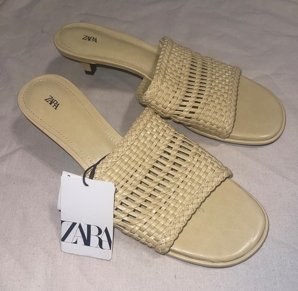 Pair of beige low-heeled sandals with a braided strap over crinkled light-colored fabric. Label and insoles feature the text ZARA.