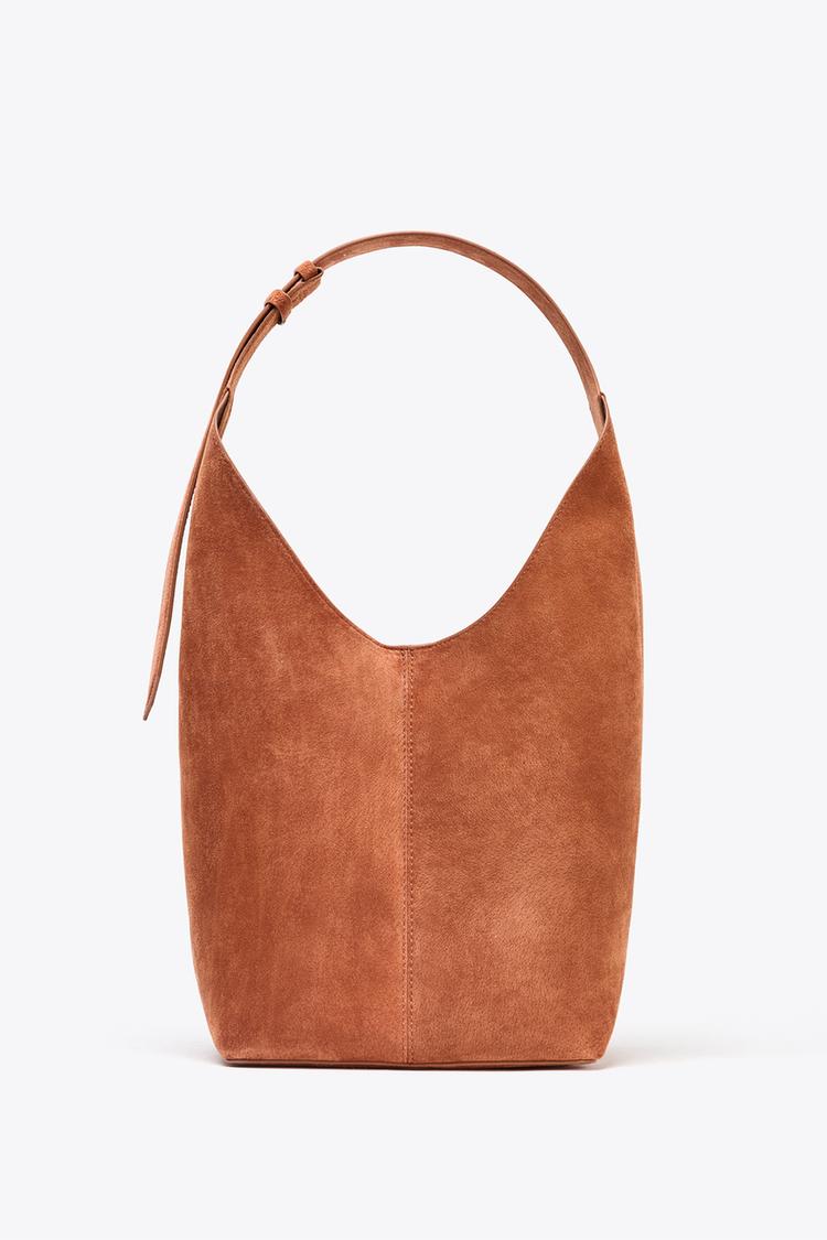 Front view of brown handbag with adjustable strap and vertical centre seam.