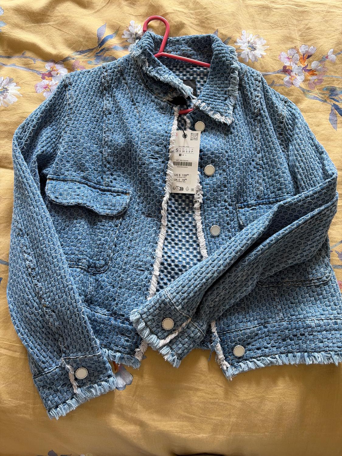 Blue textured jacket, frayed edges, over yellow floral fabric. Label: S S 26 S S P M L US $ 129.00 UK £ 79.00.