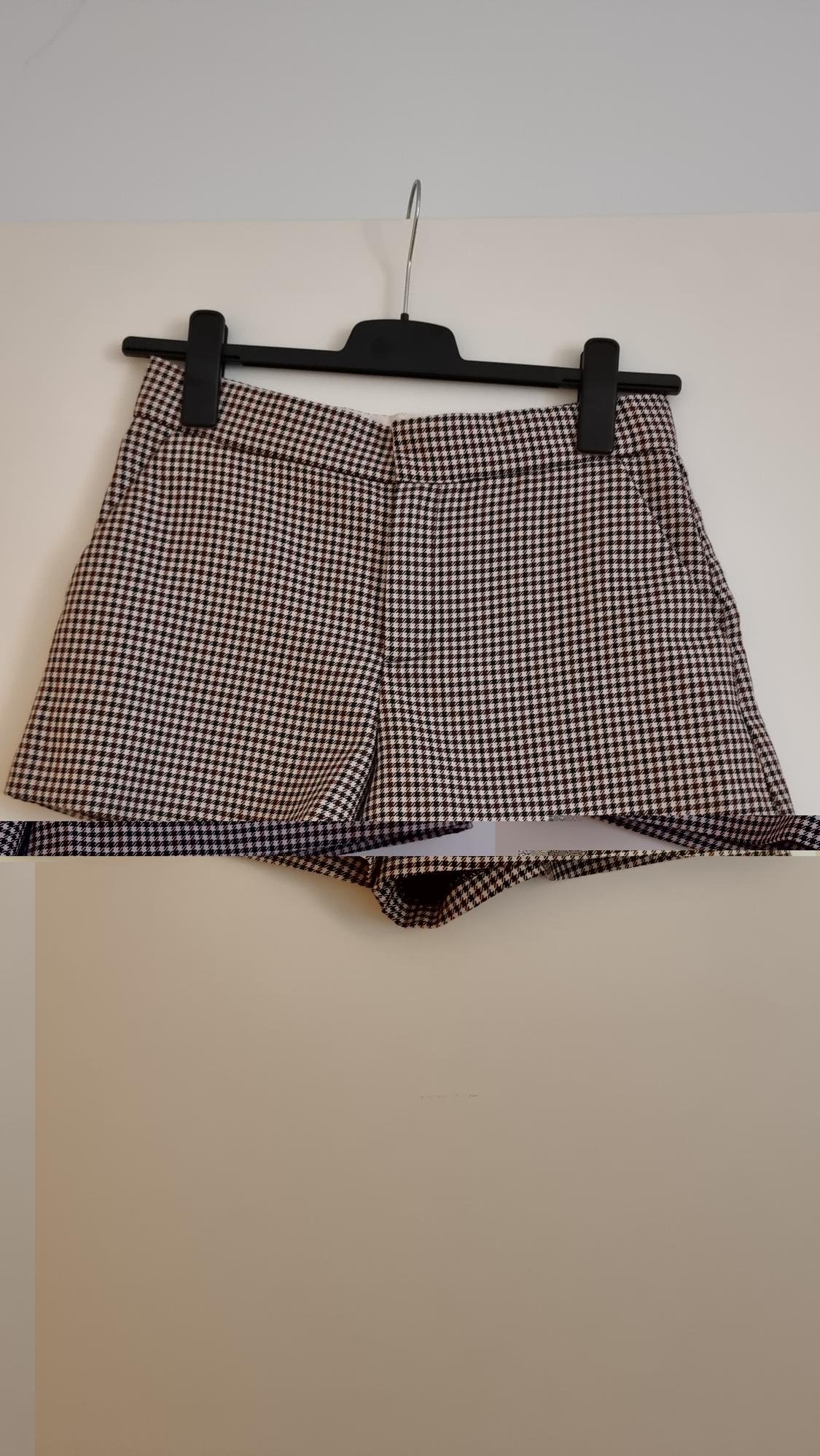 Black and white checked shorts hanging on a black hanger against a white background.