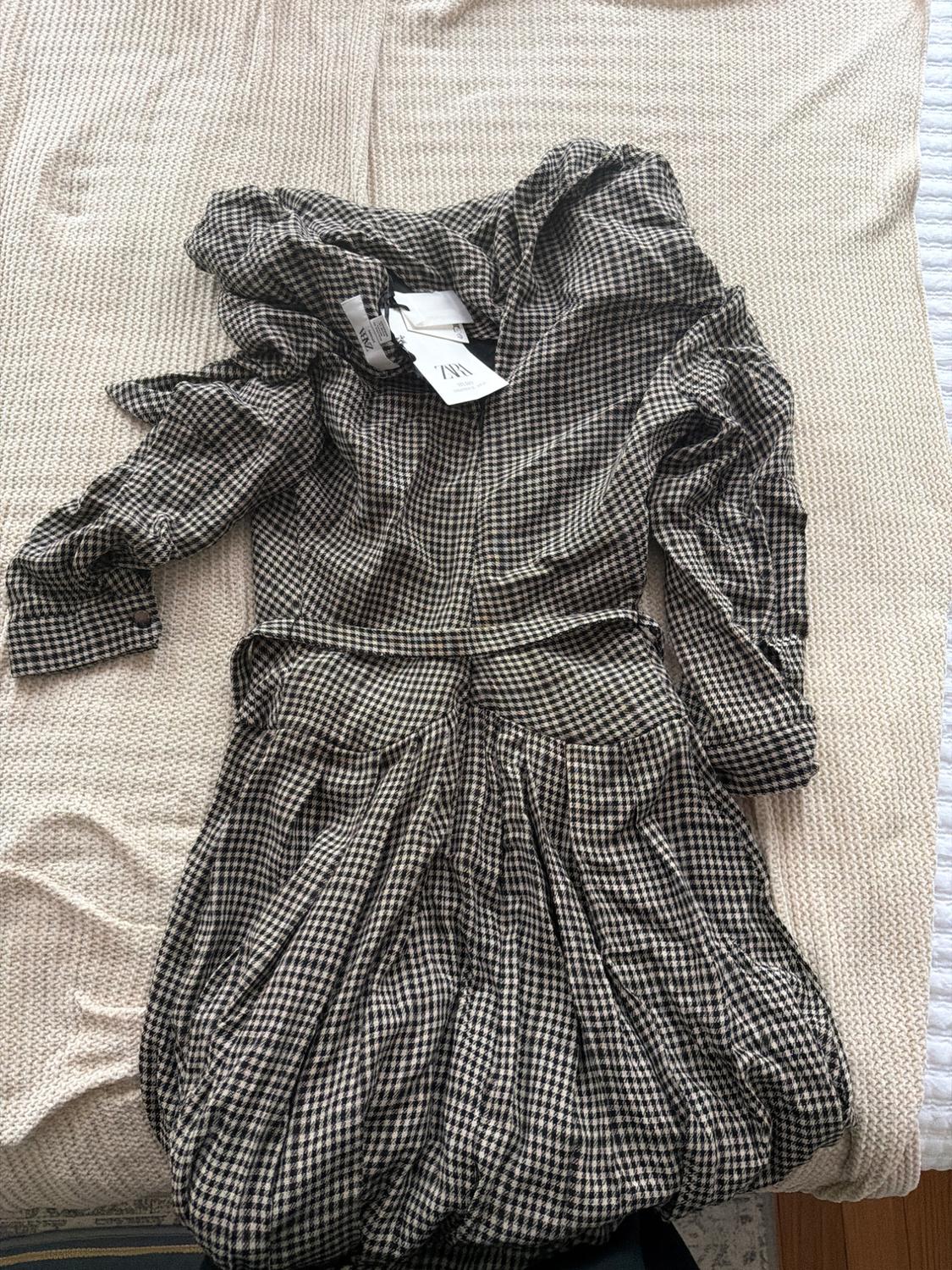 Black and white plaid dress with visible tags on a beige fabric surface.