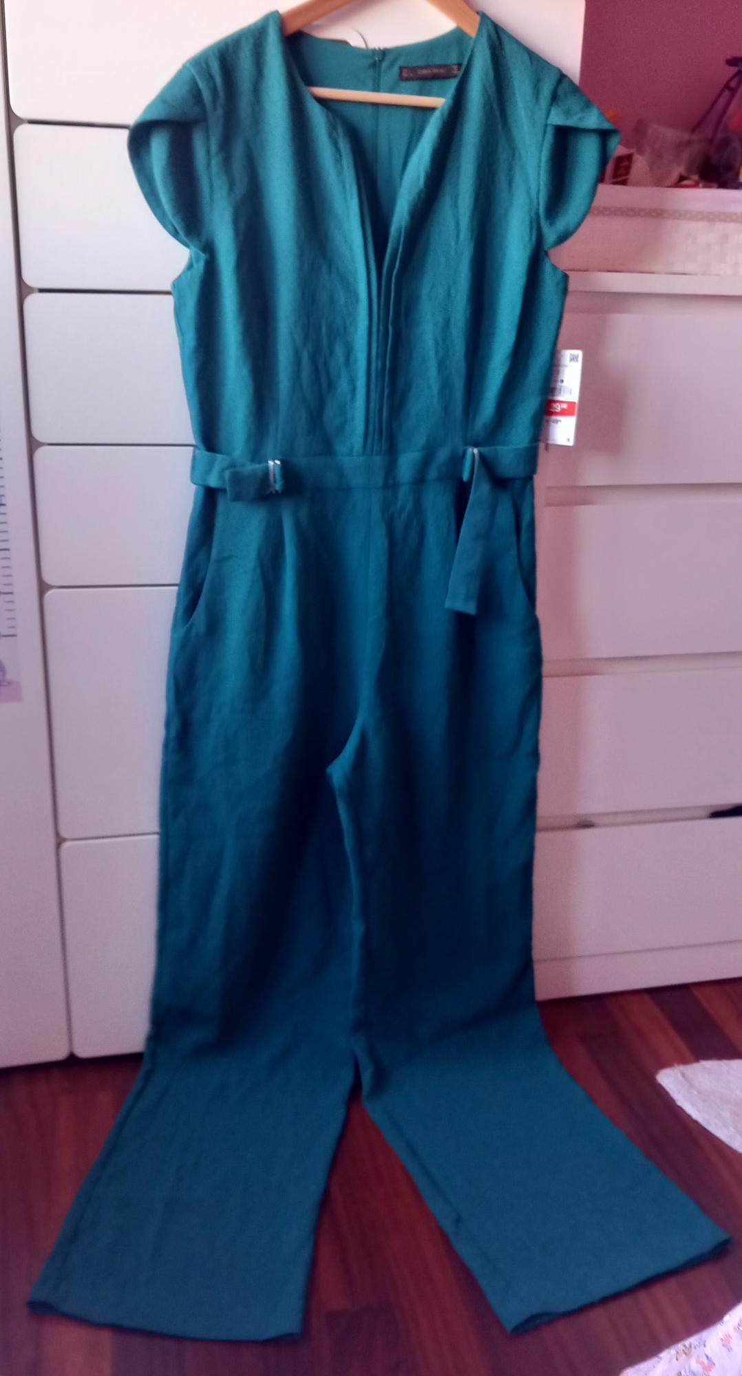 Front view of a green jumpsuit with a belt and side pockets.