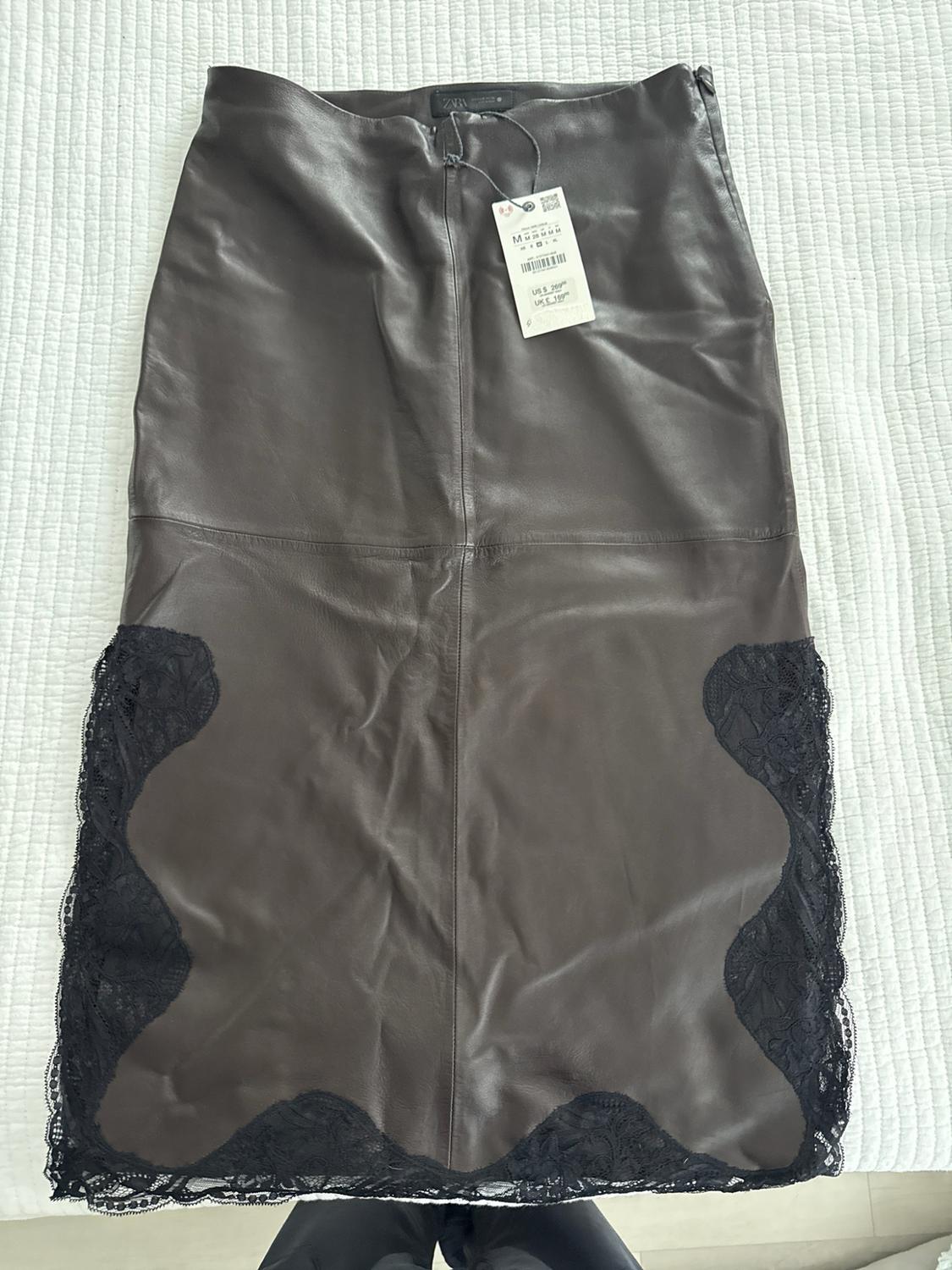Long brown skirt with black lace inserts, on a white background. Text: ZARA M US $ 299.00 UK £ 199.00.