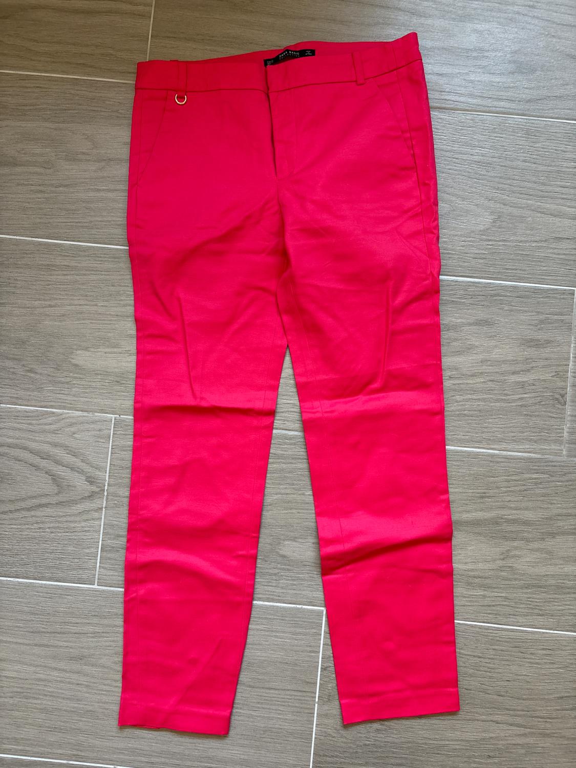 Front view of pink trousers with side pockets and a front fastening.