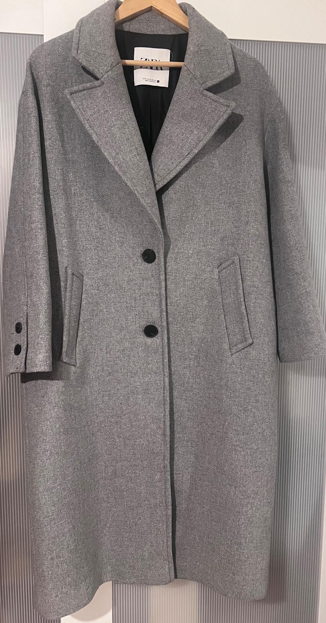 Front view of a grey coat with lapels, black buttons, and side pockets.
