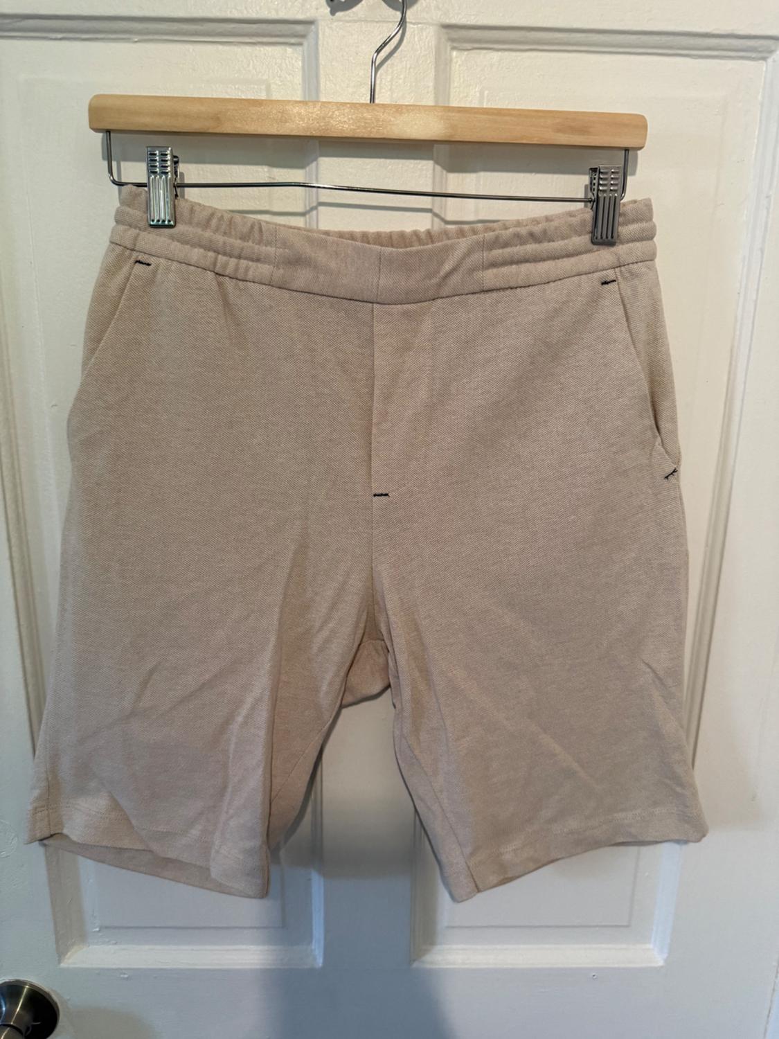 Front view of beige shorts with side pockets and elasticated waistband.