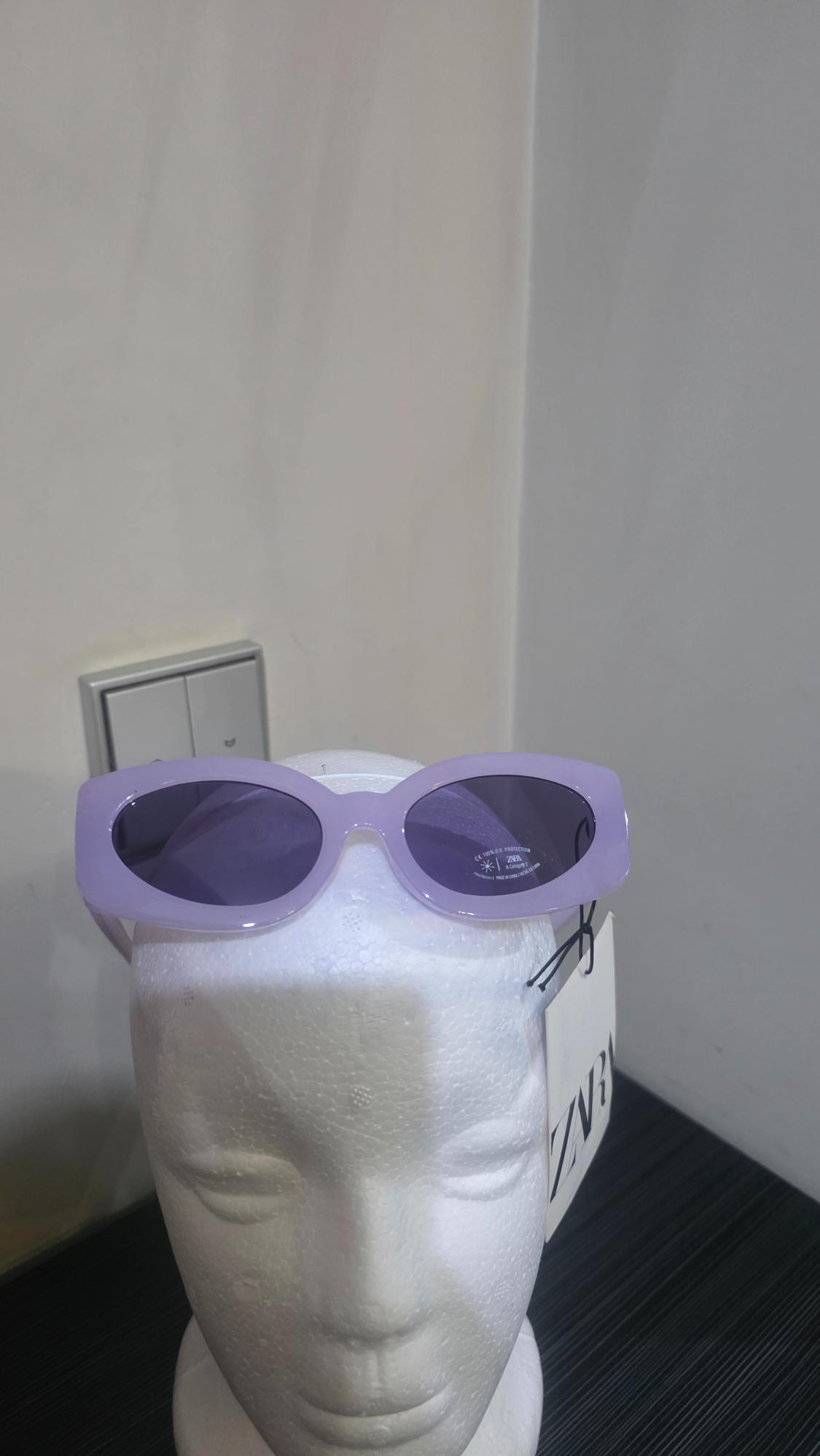 Lilac sunglasses on a white mannequin. Text: CE 100% UV PROTECTION ZARA on the lens sticker and ZARA on the swing tag.
