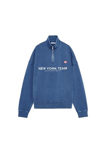 Front view of blue sweatshirt with text 'NEW YORK TEAM' and half zipper.