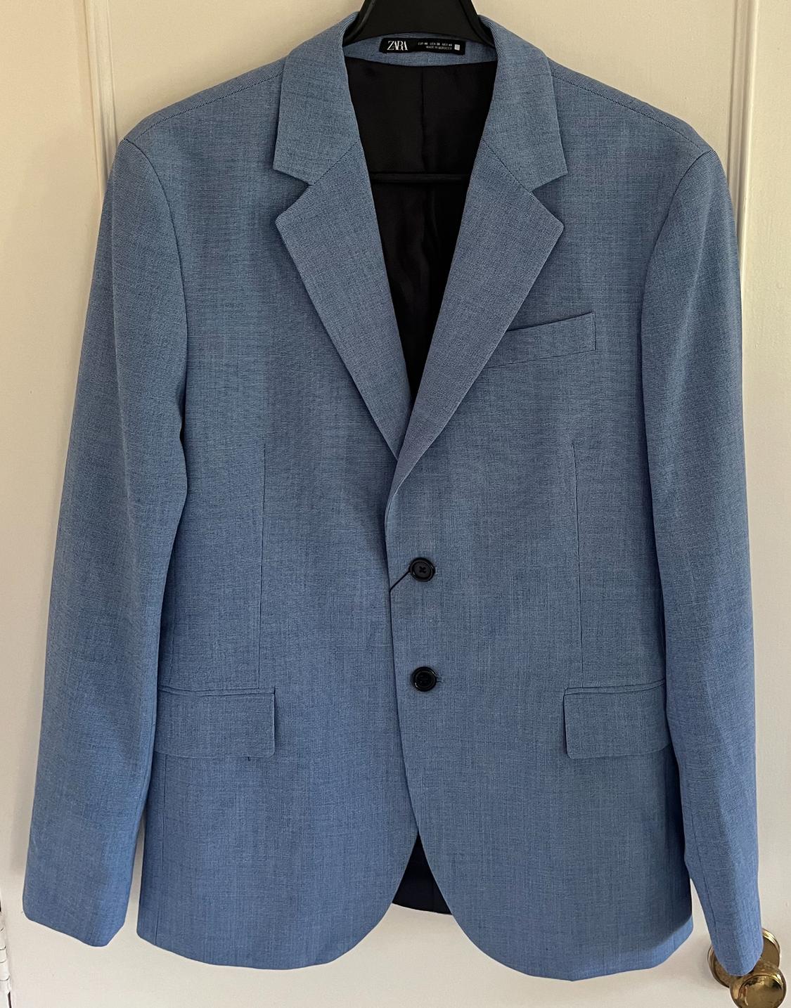 Front view of a blue jacket with lapels and two buttons, side pockets with flaps.