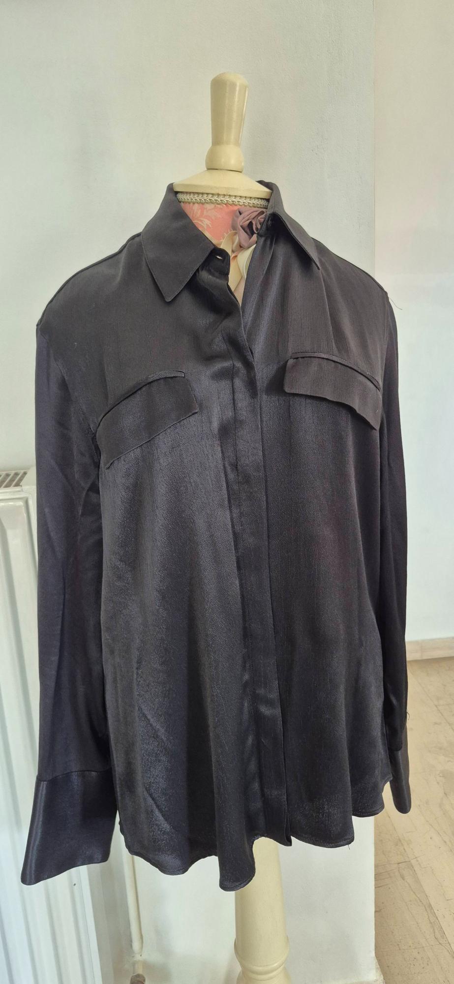 Black satin shirt with front pockets on a wooden mannequin, white background and light wooden floor.