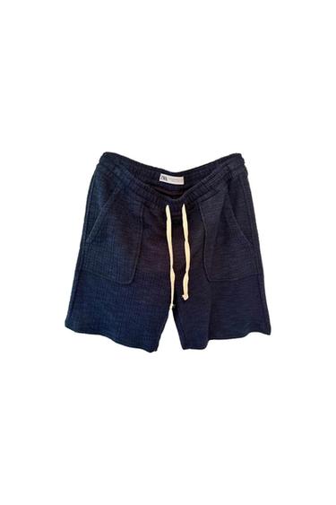 Textured navy blue shorts with white drawstring and front pockets. Visible label on waistband. White background.