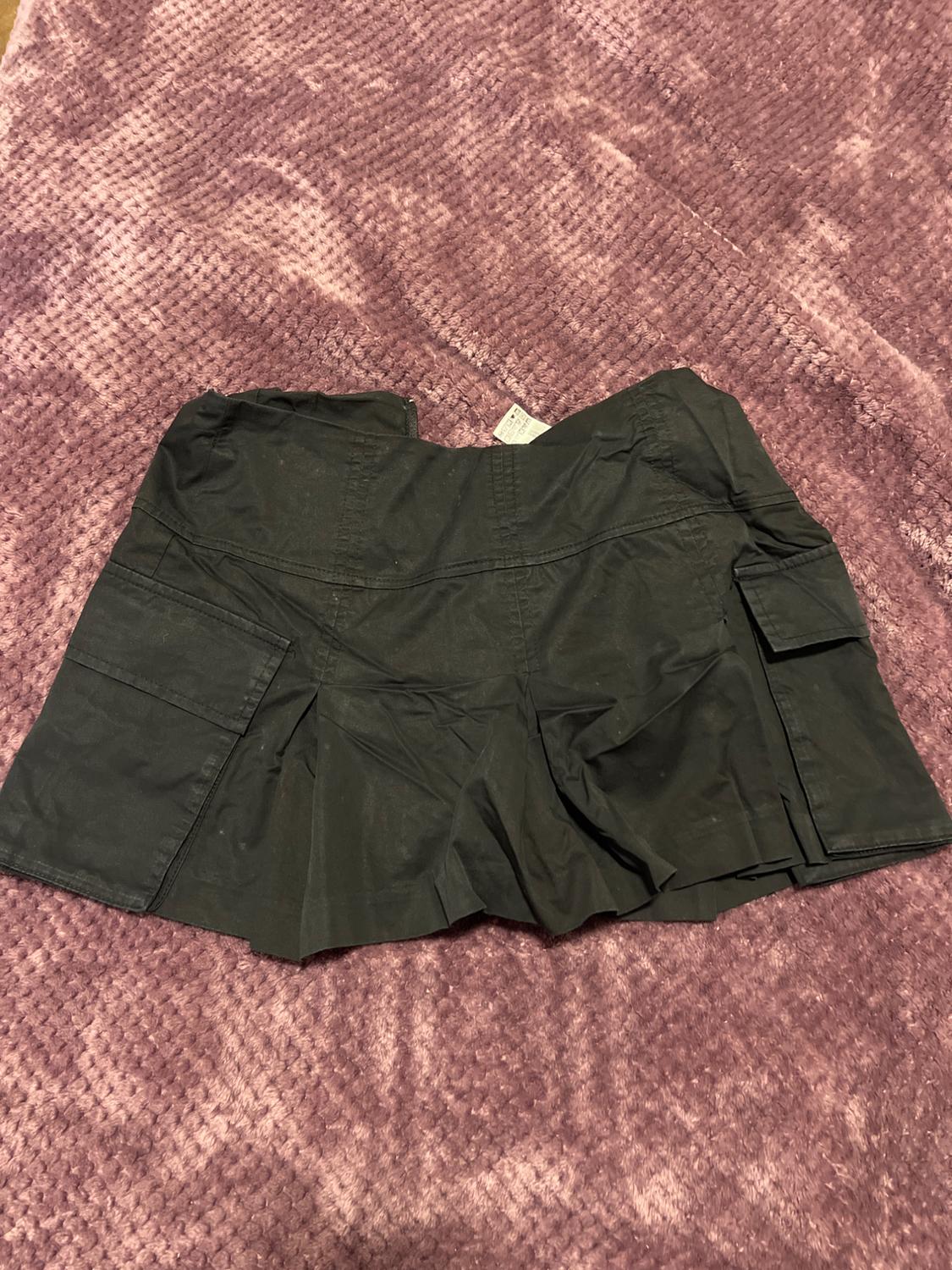 Black shorts with large pockets, placed on a soft textured, purple blanket.