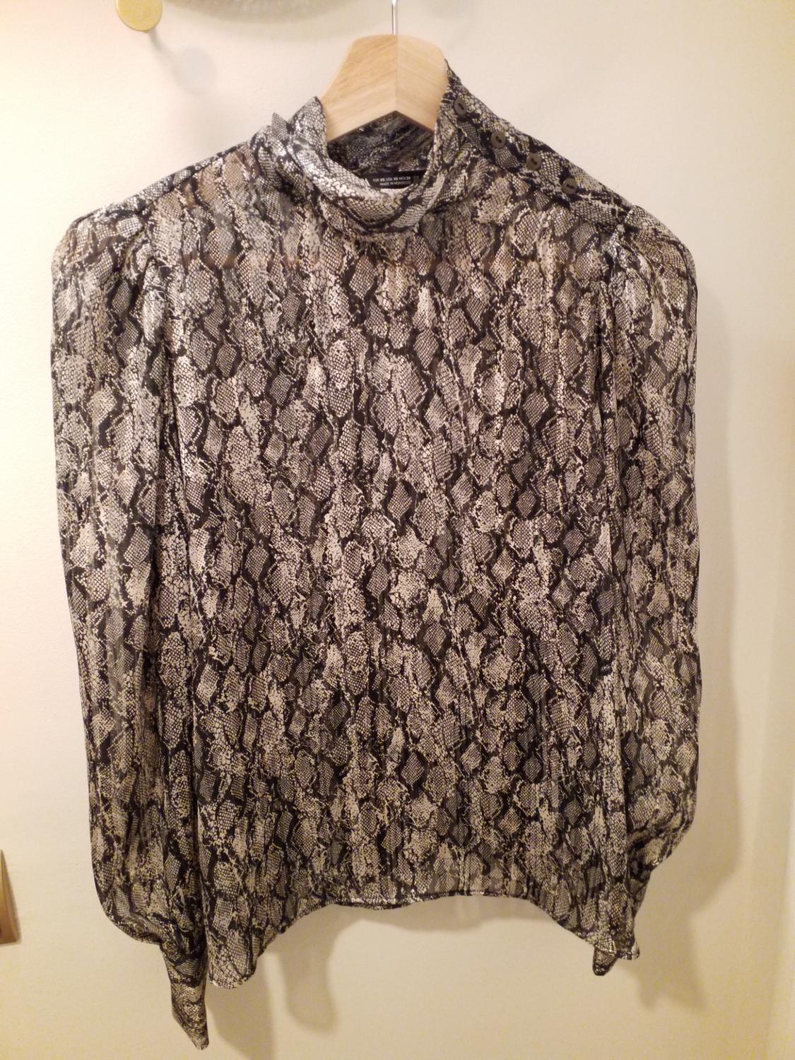 Long-sleeved blouse with a grey and black snake print, hanging on a wooden hanger against a white background.
