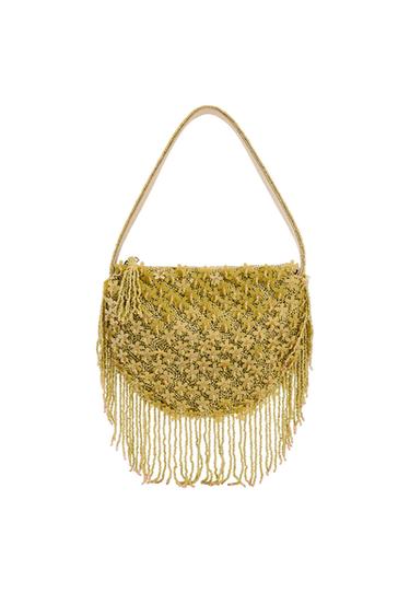 Yellow bag with floral design and long fringe at the bottom. Thin handle and semi-circular structure on a white background.