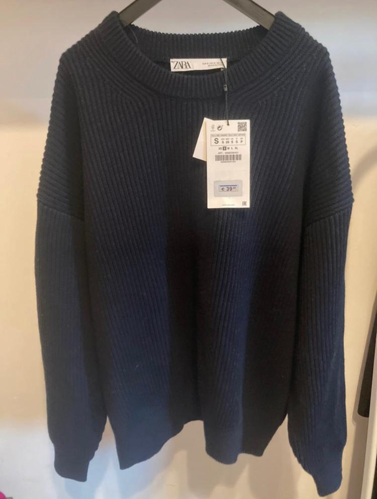 Dark blue chunky knit jumper hanging on a hanger, with a visible price tag of €39.95. Brand on tag: Zara.