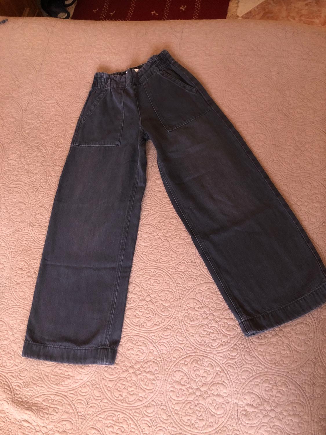 Blue denim wide-leg trousers with an elasticated waist and large pockets, on a quilt with a circular pattern design.