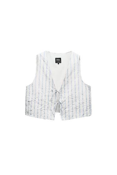 Sleeveless waistcoat with blue and white stripes, tie closure at the front. Visible label with the text "ZARA". White background.