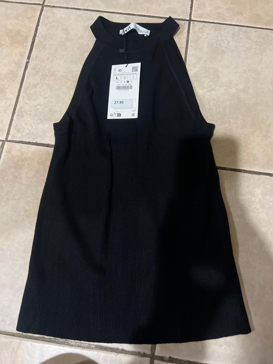 Sleeveless black dress with a high collar on a tiled floor. Visible tag with a price of 27.90.