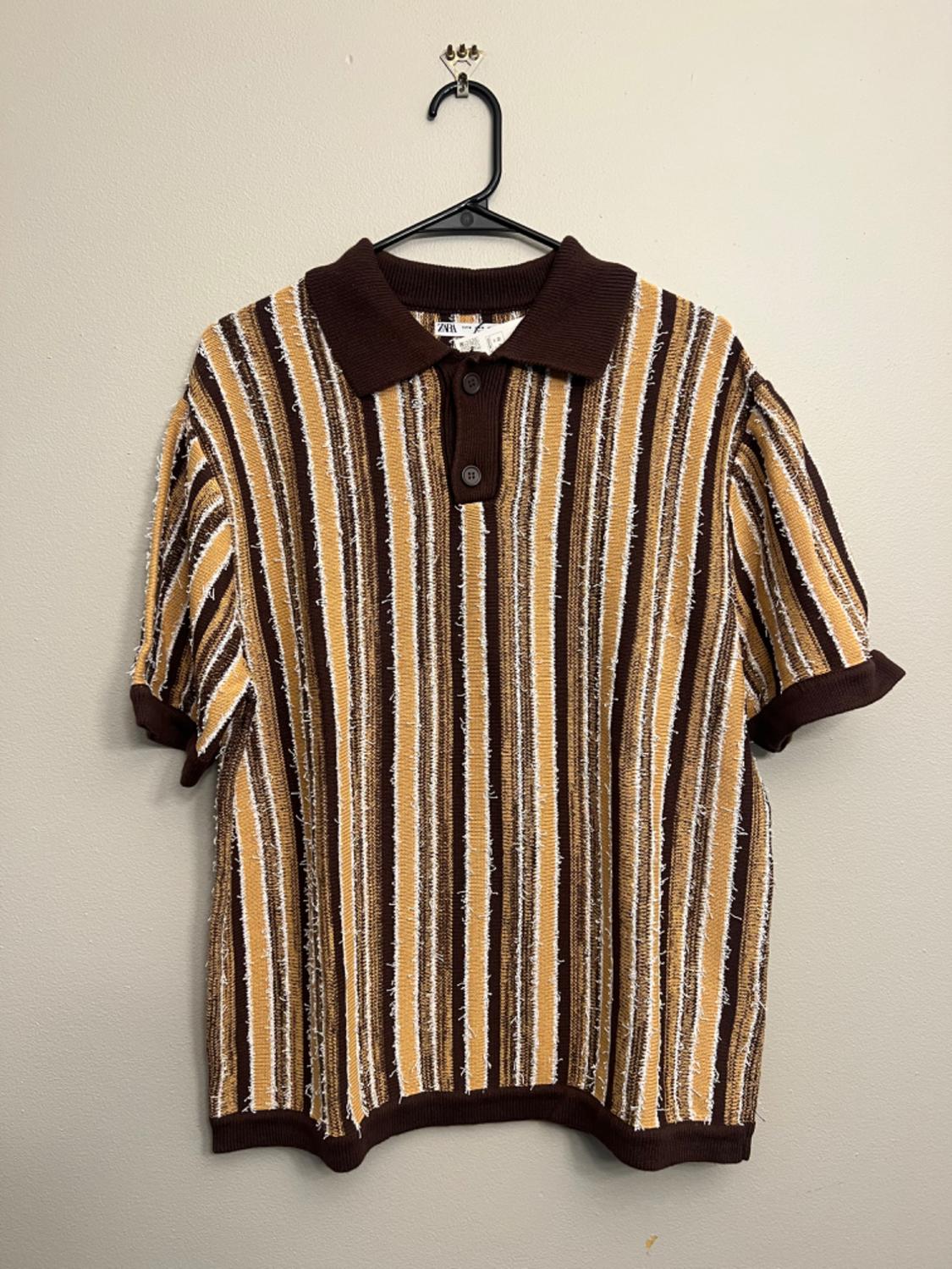 Brown, beige, and white vertical striped shirt with dark brown collar and cuffs, hanging on a black hanger.