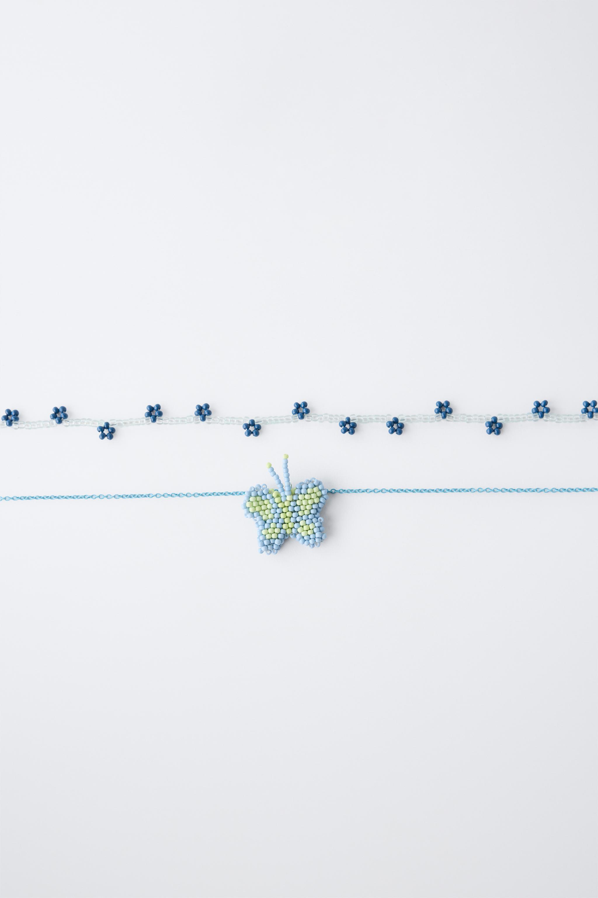 LOT DE DEUX COLLIERS FANTAISIE PAPILLON ET FLEURS