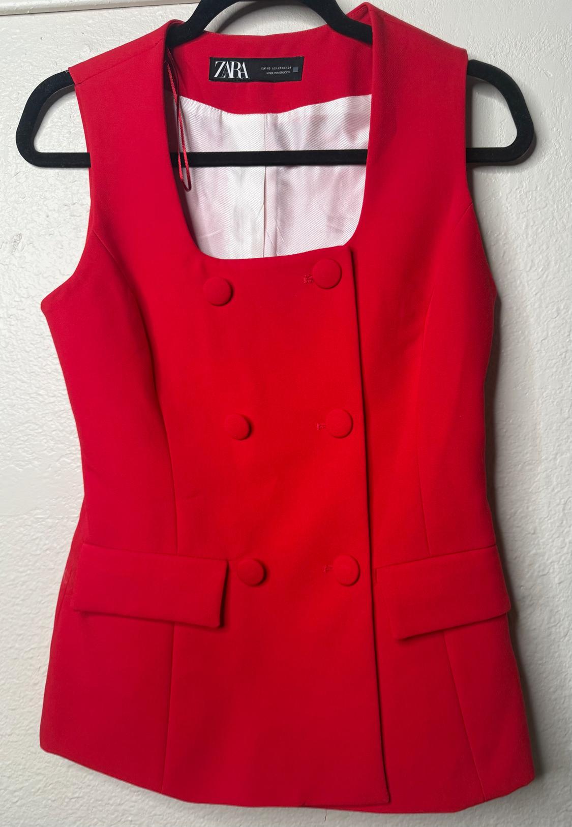 Red sleeveless double-breasted vest with front pockets, hanging on a black hanger. Visible tag: ZARA.